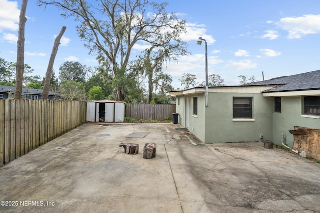 view of patio / terrace with an outbuilding, a fenced backyard, and a shed