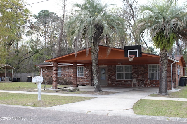 view of front of property with brick siding, concrete driveway, a front lawn, and fence