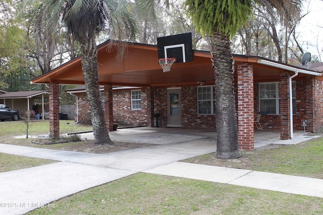 view of front facade with a carport, concrete driveway, brick siding, and a front yard