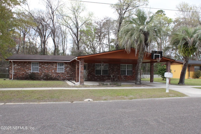 view of front of property featuring a front yard, a carport, concrete driveway, and brick siding