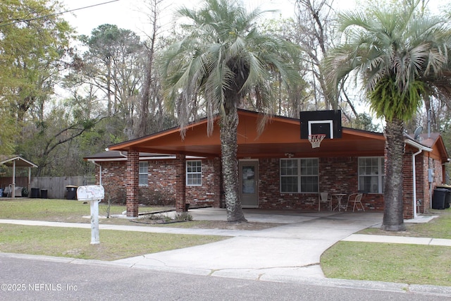 view of front of home with brick siding, concrete driveway, a front lawn, and fence