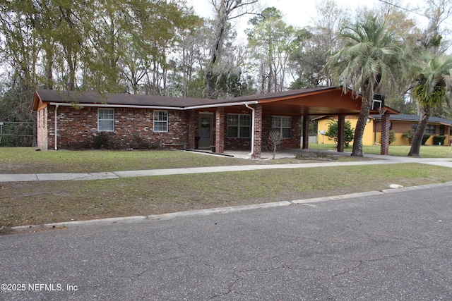 view of front of house featuring brick siding, an attached carport, concrete driveway, and a front yard