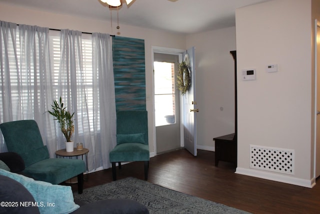 living area featuring baseboards, ceiling fan, and wood finished floors