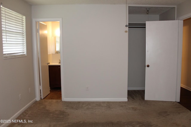 unfurnished bedroom with carpet flooring, baseboards, a closet, and connected bathroom