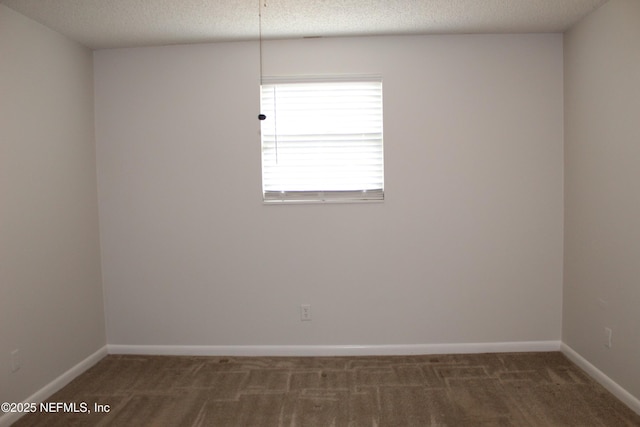 empty room featuring baseboards, carpet, and a textured ceiling