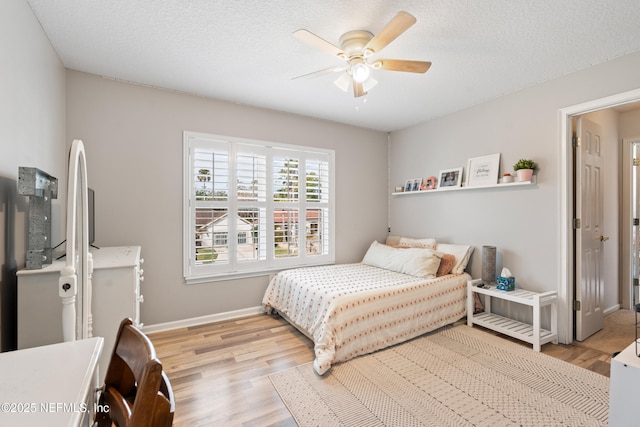 bedroom featuring a textured ceiling, ceiling fan, wood finished floors, and baseboards