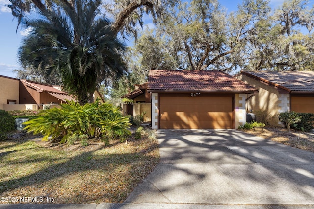 mid-century home with a garage, stucco siding, concrete driveway, and a tiled roof