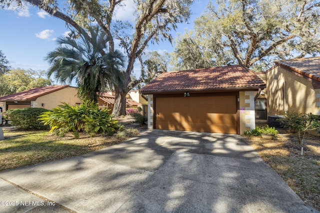 view of front of home with a tiled roof, stone siding, a detached garage, and stucco siding