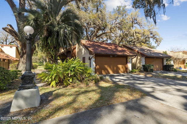 view of front of home featuring a garage, a tiled roof, and stucco siding