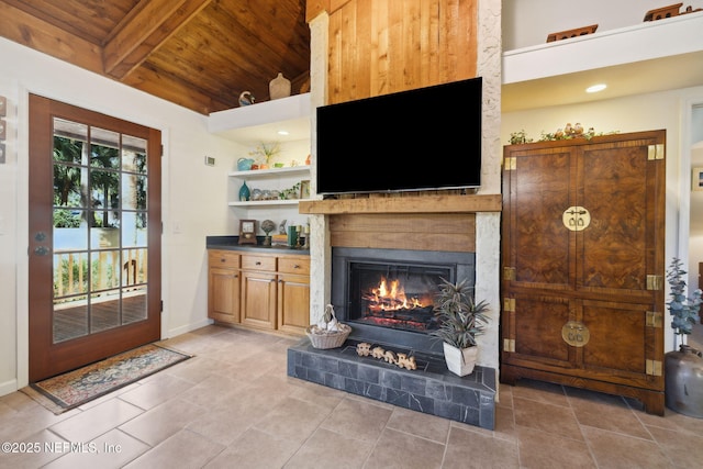 living area with light tile patterned floors, wood ceiling, baseboards, a lit fireplace, and beam ceiling