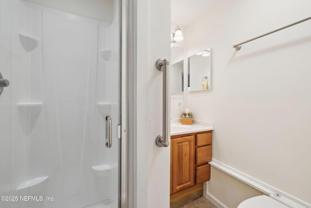 full bathroom featuring a stall shower, baseboards, vanity, and toilet