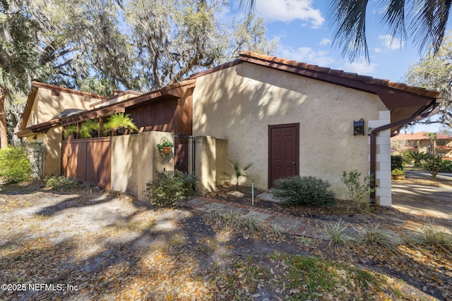 view of side of home featuring a tile roof and stucco siding