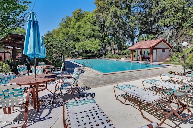 pool featuring a patio area and an outbuilding