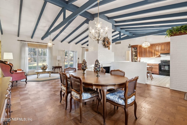 dining room featuring lofted ceiling with beams, an inviting chandelier, and a glass covered fireplace