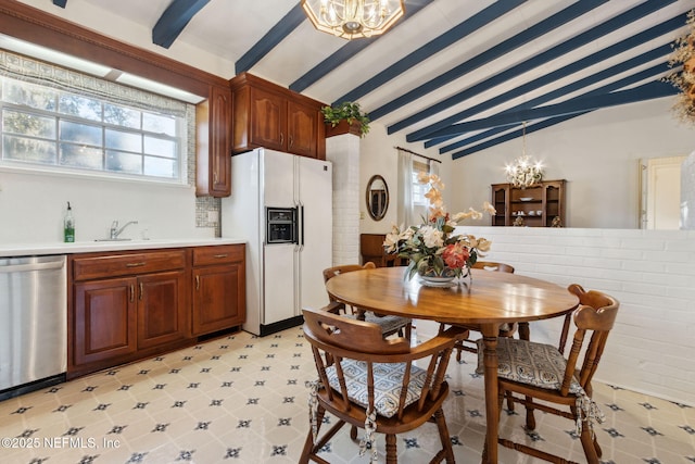 kitchen featuring white refrigerator with ice dispenser, a notable chandelier, lofted ceiling with beams, stainless steel dishwasher, and a sink