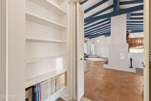 hallway with lofted ceiling with beams and built in shelves