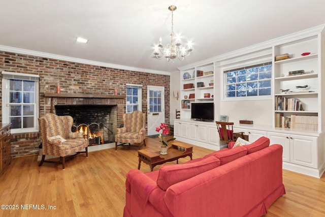 living room featuring a chandelier, brick wall, a fireplace, light wood-style floors, and ornamental molding