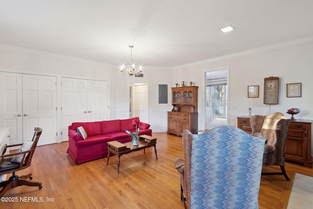 living area featuring light wood finished floors, crown molding, and an inviting chandelier