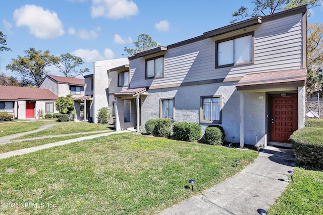townhome / multi-family property with stucco siding and a front yard