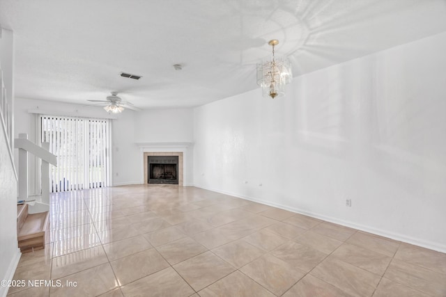 unfurnished living room with visible vents, baseboards, light tile patterned floors, ceiling fan with notable chandelier, and a tile fireplace