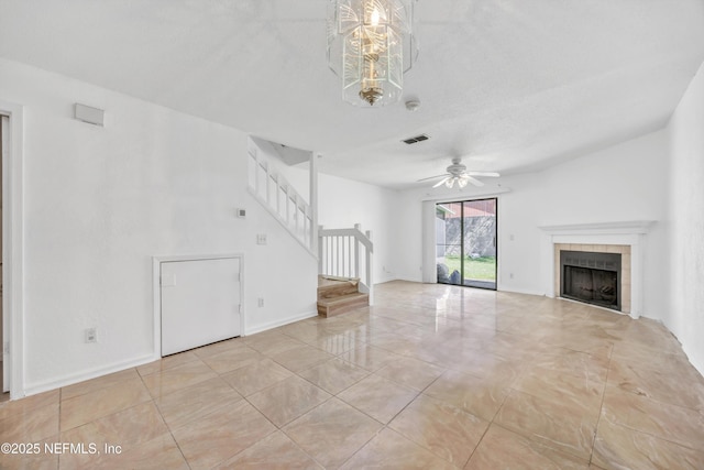 unfurnished living room featuring visible vents, a ceiling fan, stairway, baseboards, and a tile fireplace