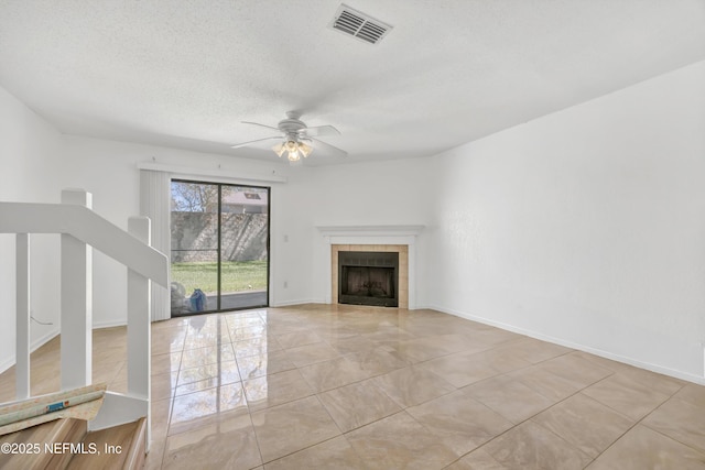 unfurnished living room featuring a ceiling fan, baseboards, visible vents, a fireplace, and a textured ceiling