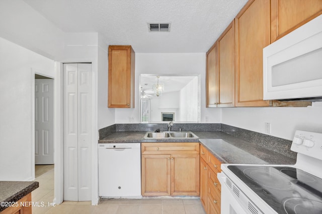 kitchen featuring dark countertops, visible vents, white appliances, a textured ceiling, and a sink