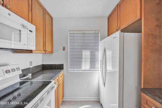 kitchen featuring white appliances, light tile patterned floors, brown cabinetry, and a textured ceiling