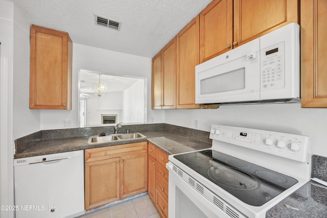 kitchen featuring dark countertops, visible vents, white appliances, and a sink