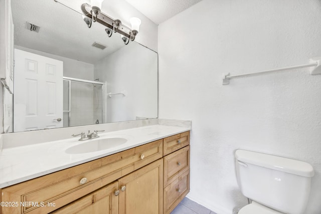 bathroom featuring visible vents, a stall shower, toilet, and vanity