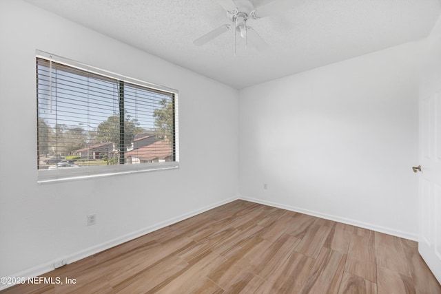 empty room featuring baseboards, a textured ceiling, wood finished floors, and a ceiling fan