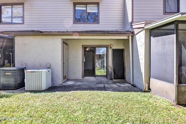 doorway to property featuring a lawn, central AC, and stucco siding