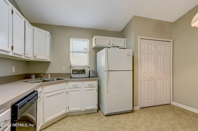 kitchen featuring a toaster, a sink, white cabinetry, freestanding refrigerator, and dishwasher