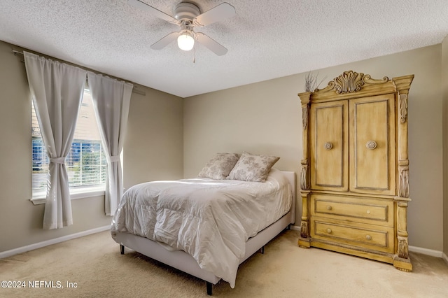 bedroom featuring light carpet, ceiling fan, a textured ceiling, and baseboards