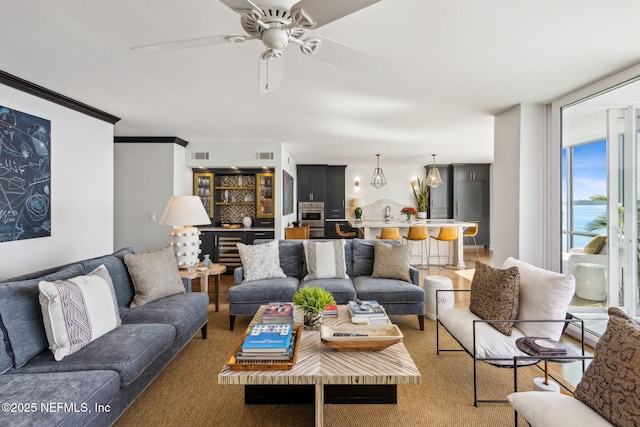 living area with a ceiling fan, visible vents, and a wall of windows