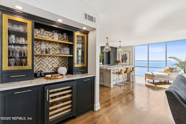 bar with a dry bar, beverage cooler, tasteful backsplash, visible vents, and wood finished floors