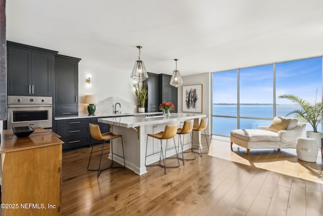 kitchen featuring expansive windows, a kitchen island, wood finished floors, oven, and a kitchen bar