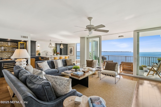 living room with a water view, plenty of natural light, a wall of windows, and wood finished floors