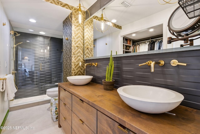 bathroom with visible vents, a sink, a shower stall, and double vanity