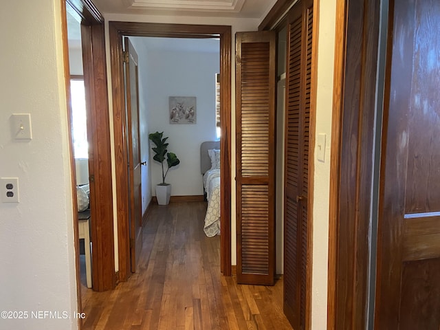 corridor featuring wood-type flooring and baseboards