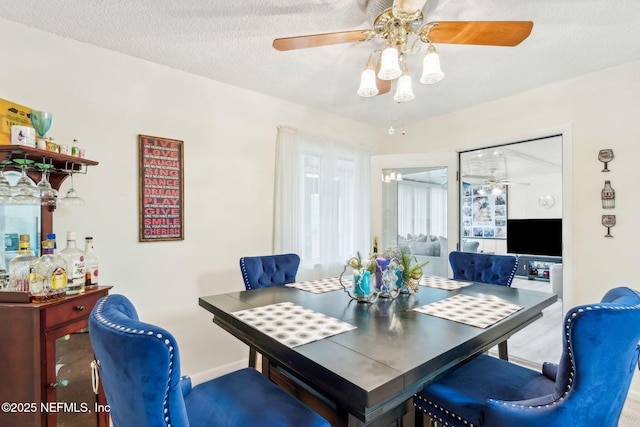 dining room with baseboards, a ceiling fan, and a textured ceiling