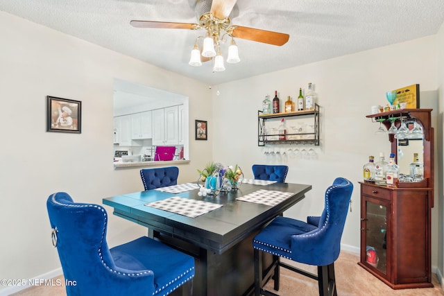 dining area featuring light carpet, ceiling fan, a textured ceiling, and baseboards