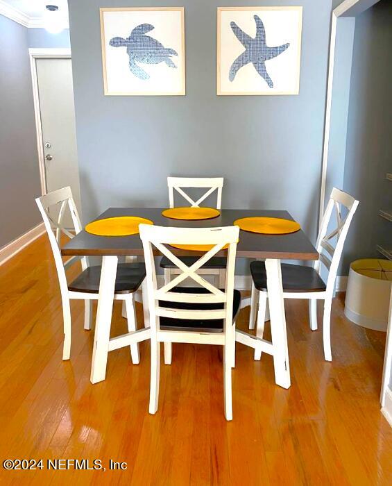 dining area featuring crown molding, wood finished floors, and baseboards