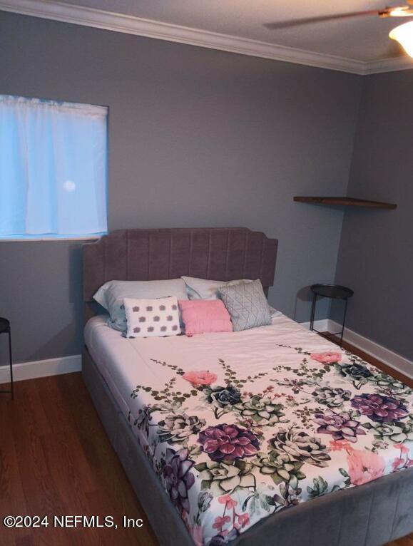 bedroom featuring baseboards, ornamental molding, ceiling fan, and wood finished floors