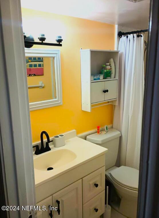 full bath with a shower with curtain, vanity, and toilet