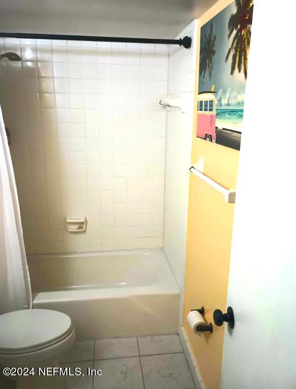 full bath featuring toilet, tile patterned flooring, and shower / bath combo