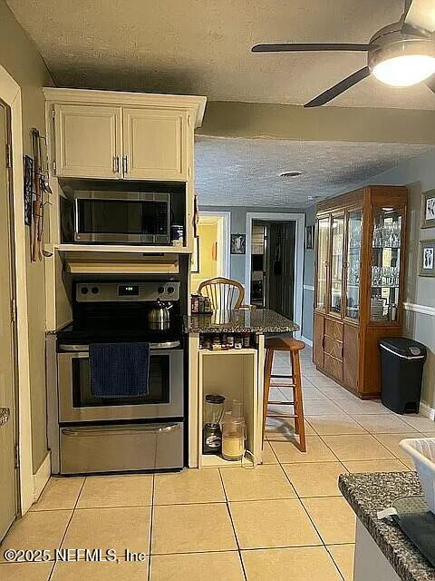 kitchen featuring light tile patterned floors, ceiling fan, electric range, and built in microwave