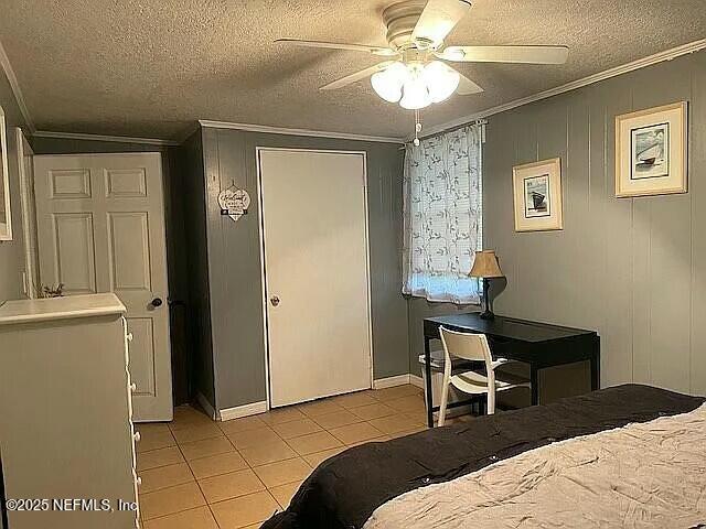 bedroom featuring light tile patterned floors, a closet, crown molding, and a textured ceiling