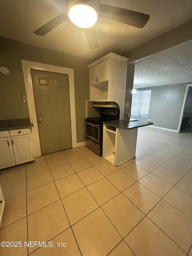 kitchen featuring light tile patterned floors, baseboards, dark stone counters, stainless steel electric range oven, and a textured ceiling