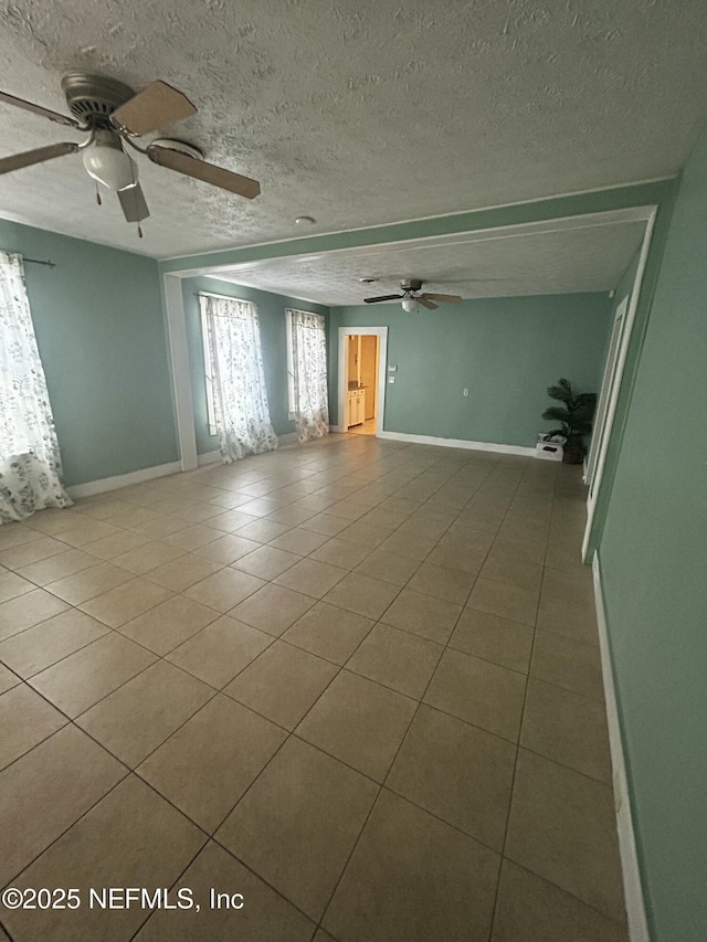 tiled spare room featuring ceiling fan, baseboards, and a textured ceiling